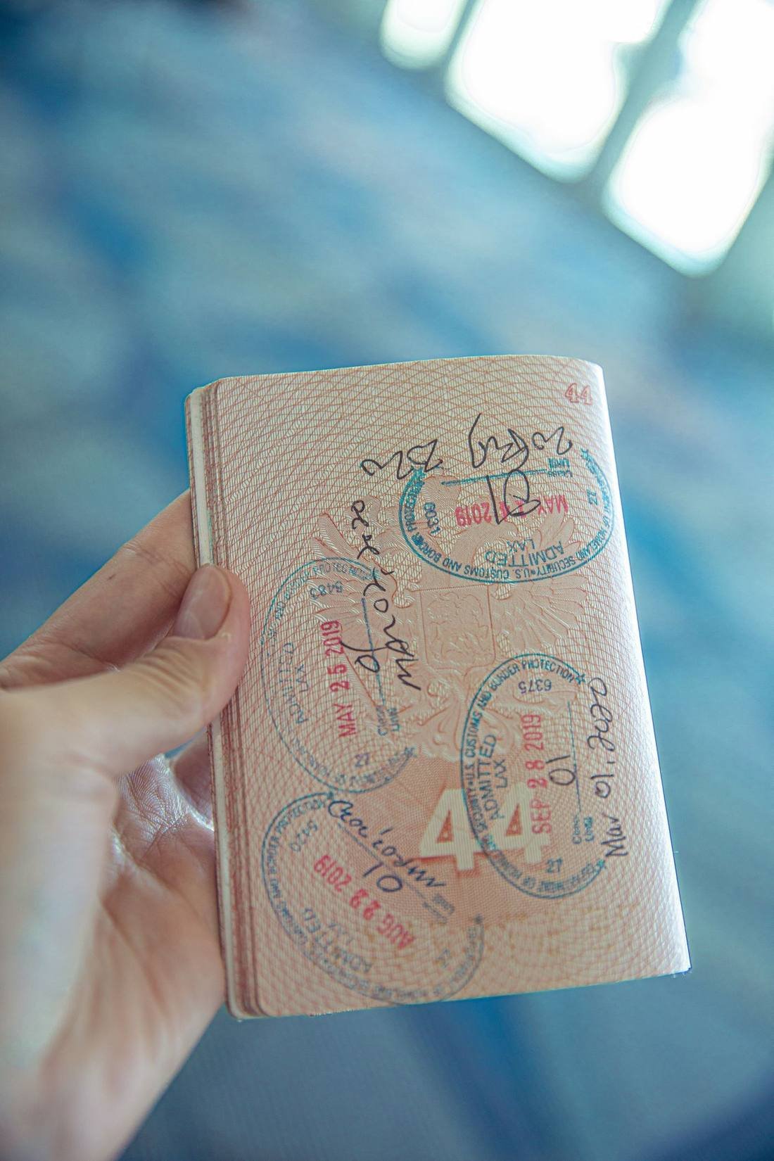 Passport with visa entry stamps, held in hand